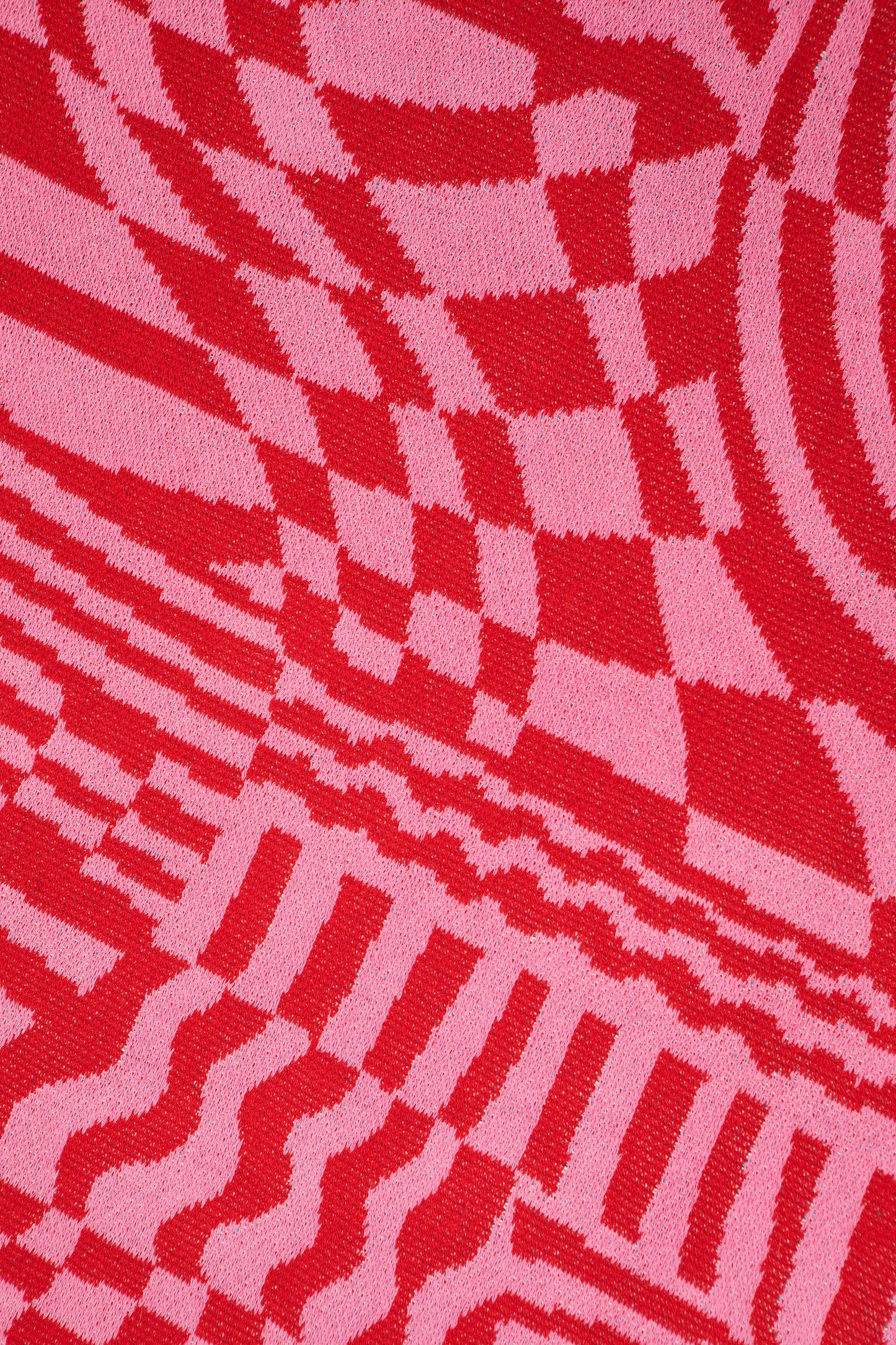 Close up of Wiggles and Waves showing the red and pink abstract designs and knit pattern.