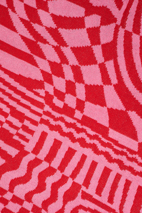 Close up of Wiggles and Waves showing the red and pink abstract designs and knit pattern.