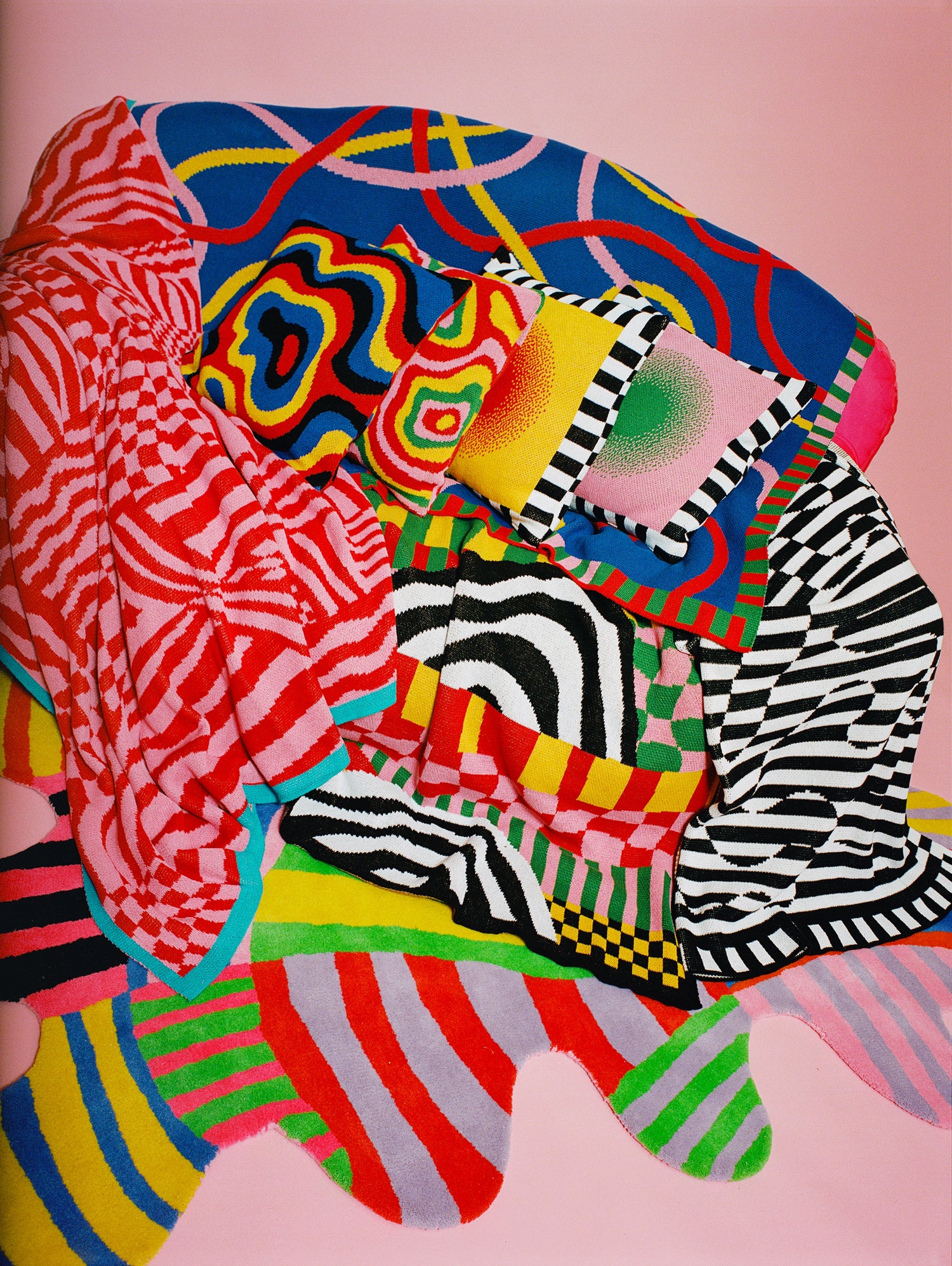 Detail image showing pile of many pillows and blankets on top of the Squiggle Stripe Rug.
