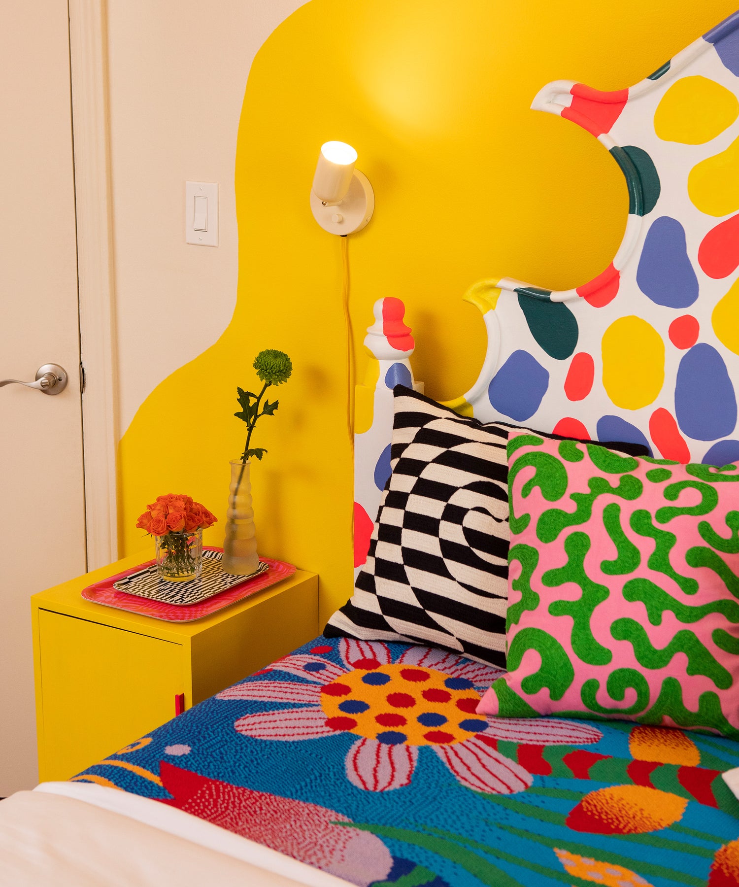Image of a bed made with the Best Buds Blanket in a colorful bedroom. On top of the blanket sits the Dazzle and Silly Squiggles Pillow Covers.