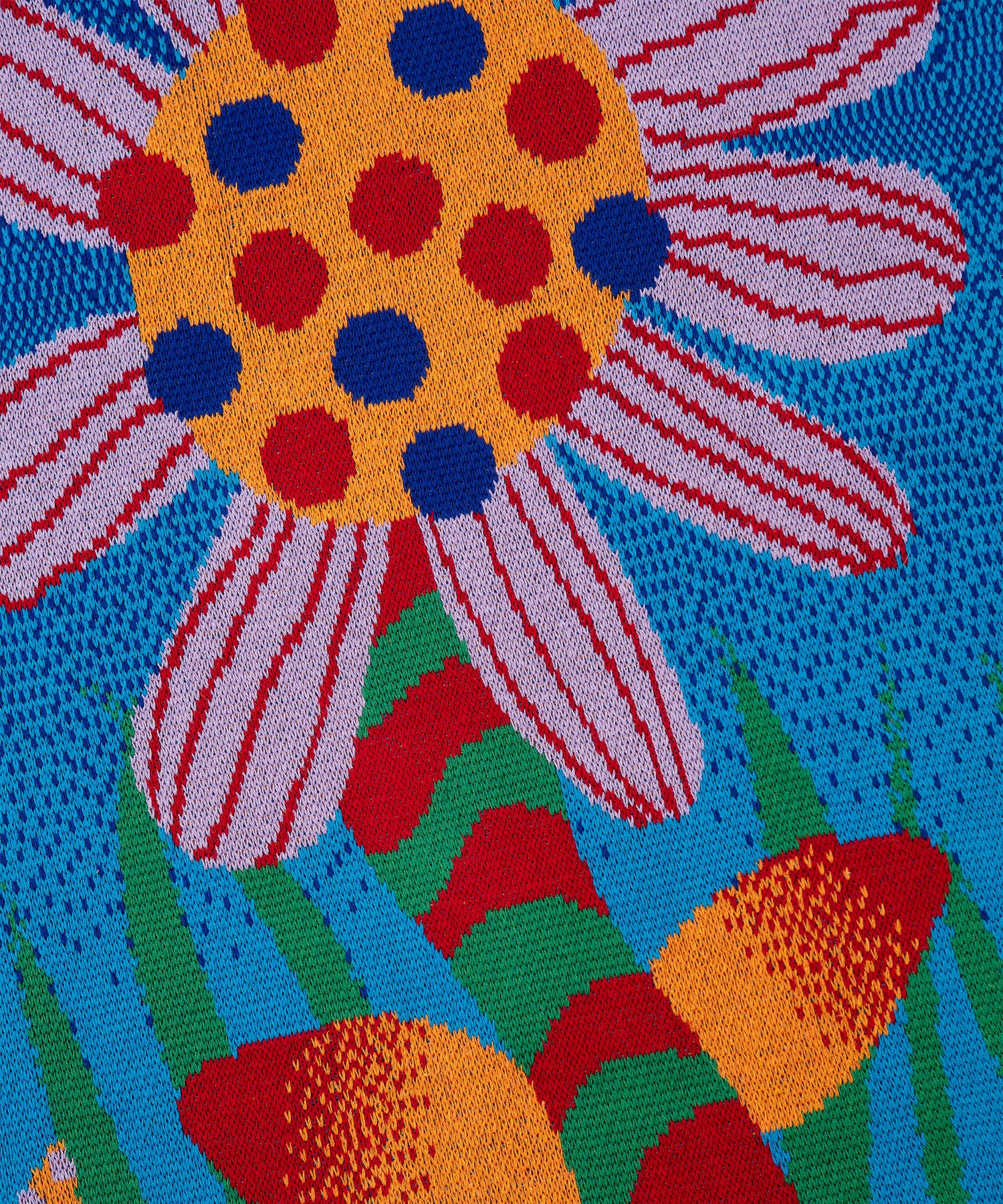 Close up image of Best Buds Blanket showing a light purple flower with blue and red dots on top of the yellow flower center. The flower is sitting on a red and green striped stem with two red and yellow gradient leaves.